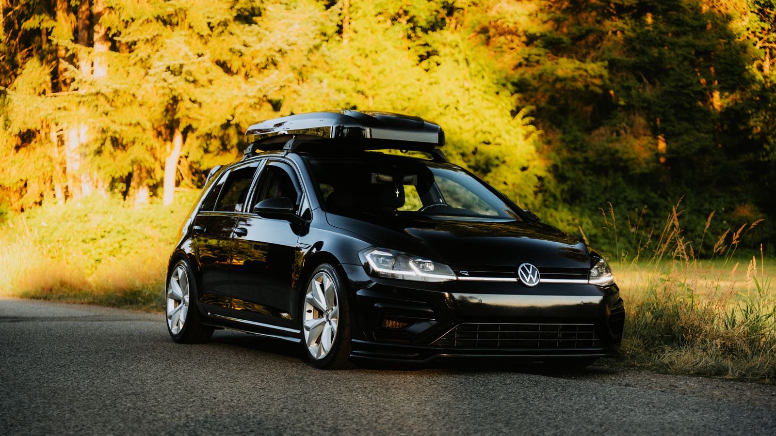 Auto mit Dachbox auf einer Straße im Abendlicht