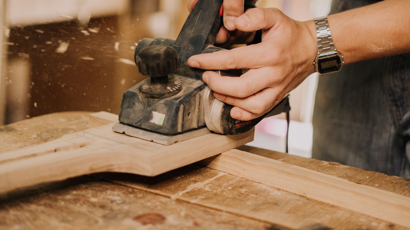 Handwerker bearbeitet ein Holzbrett mit einem Elektrohobel